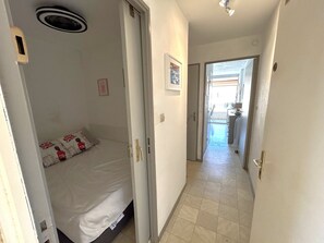Ein Hotelzimmer mit Bett, Tür, Flur und Blick ins Freie.