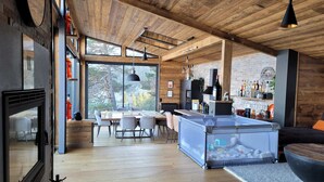 Cocina moderna con una isla grande, techo de madera y vista a los árboles a través de amplios ventanales.