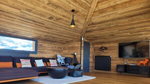 Una sala de estar acogedora con techo de madera, un conjunto de sofás, una mesa de centro, una chimenea y un televisor.
