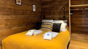 Una habitación con paneles de madera, una cama, dos lámparas de pared y un cuadro enmarcado.