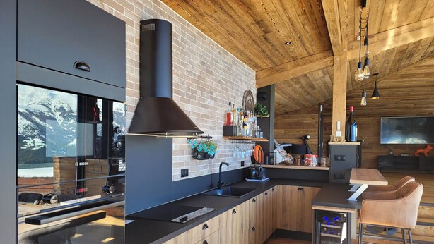 Una cocina moderna con salpicadero de ladrillo, armarios de madera y una estufa Bosch de gran tamaño.