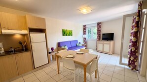 Eine kleine Küche mit Kühlschrank, Herd und Essbereich inklusive Stühle und Tisch.