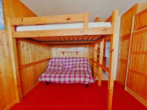 A bunk bed with a checkered bedspread in a wooden room with red carpeting. - Charming studio, mountain view - 3 guests (Les Saisies)