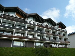A multi-story hotel with balconies, a flat roof, and a clear sky. - Charming studio, mountain view - 3 guests (Les Saisies)