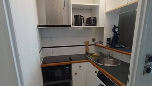 A compact kitchen with a microwave, oven, sink, and a washing machine. - T2 sea view, parking - 4 guests (Canet-Plage)