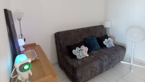 A living room with a sofa, a side table with a lamp, and a floor lamp. - T2 sea view, parking - 4 guests (Canet-Plage)