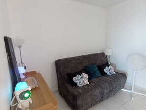 Ein Wohnzimmer mit einer Couch, einem Beistelltisch mit Lampe und einer Stehlampe.