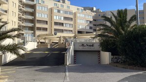 A multi-story building with balconies, a gated entrance, and a sign indicating 'Grand Sud.' - T2 sea view, parking - 4 guests (Canet-Plage)