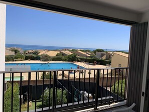 A balcony with a view of a swimming pool and the sea. - Studio cabin sea view, pets and parking - 4 guests (Fleury-Saint-Pierre-la-Mer)