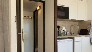 Eine kompakte Küche mit Einbauofen, Spüle und modernem Wasserhahn sowie einer kleinen Arbeitsfläche mit verschiedenen Gegenständen.