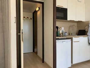 A compact kitchen with a built-in oven, a sink with a modern faucet, and a small countertop with various items. - Studio cabin sea view, pets and parking - 4 guests (Fleury-Saint-Pierre-la-Mer)