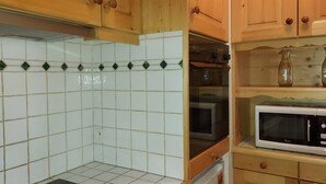 Eine Küche mit Holzausstattung, einer Mikrowelle, einem Backofen und einer schwarzen Arbeitsplatte.