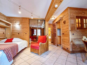 A wooden cabin room with a bed, a chair, and a small table. - Cozy apartment in Valmorel center - 4 guests (Valmorel)