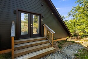 A modern house with a dark exterior, a double door, and a wooden staircase leading to the entrance. - King Studio, Fast WIFI, Peaceful, Secluded Nature, Pets (Alexander)