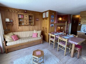 A cozy cabin interior with a sofa, dining table, and kitchen area.