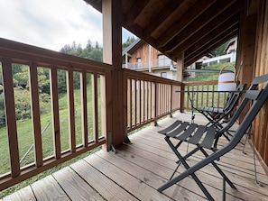 A wooden deck with a railing, a table, and two lounge chairs. - Cosy apartment with mountain view - 7 guests (Valmorel)