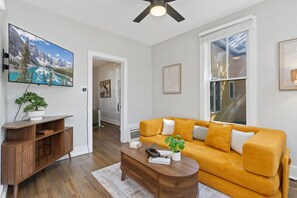 Ein Wohnzimmer mit Sofa, Couchtisch, Fernseher und Kunstwerken.
