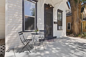 A house with a porch, a table with chairs, and a bottle of wine.
