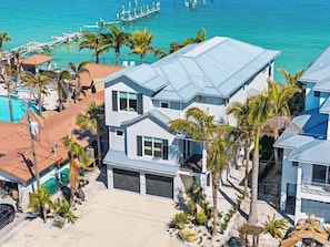 A coastal residential area with houses, a swimming pool, and a dock extending into the water.
