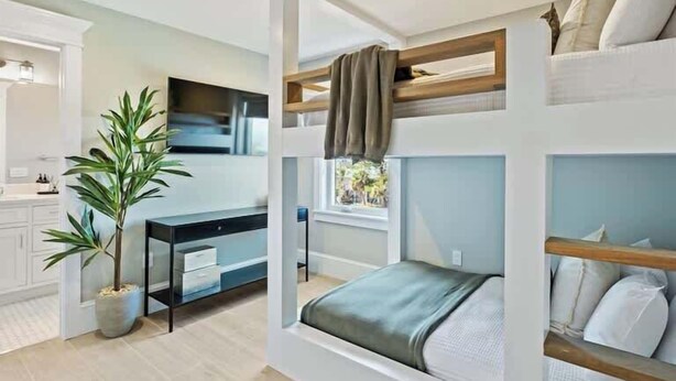 A compact bedroom with bunk beds, a desk, and a potted plant.