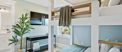 A compact bedroom with bunk beds, a desk, and a potted plant.