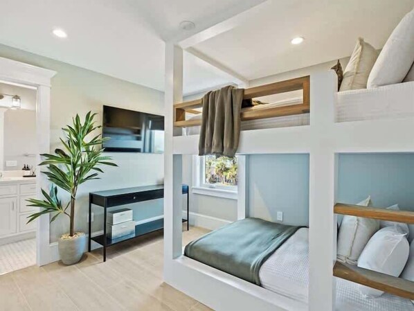 A compact bedroom with bunk beds, a desk, and a potted plant.