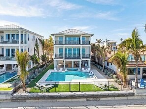 Un hôtel à plusieurs étages doté d’une piscine, de palmiers et surplombant un ciel dégagé.
