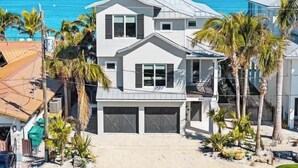 A two-story house with a garage, a balcony, and a view of the ocean.
