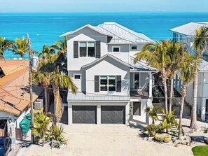 A two-story house with a garage, a balcony, and a view of the ocean.