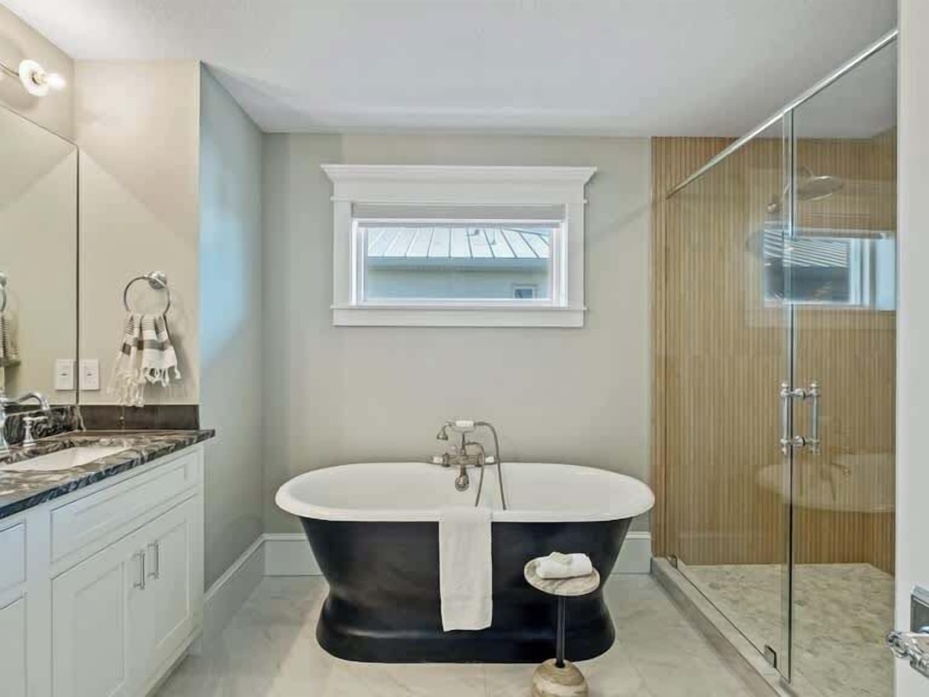 Une salle de bain moderne avec une baignoire sur pieds, une douche à parois de verre et une fenêtre au-dessus du lavabo.