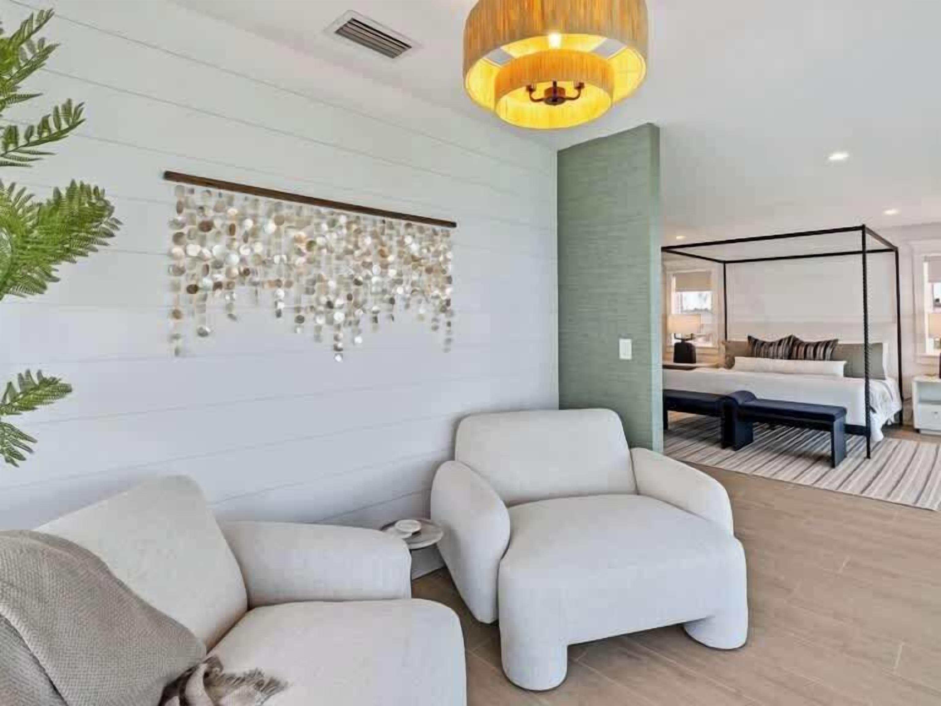 Une chambre d’hôtel moderne avec un grand lit, un coin salon avec un banc et une décoration murale.