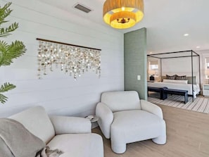 Une chambre d’hôtel moderne avec un grand lit, un coin salon avec un banc et une décoration murale.