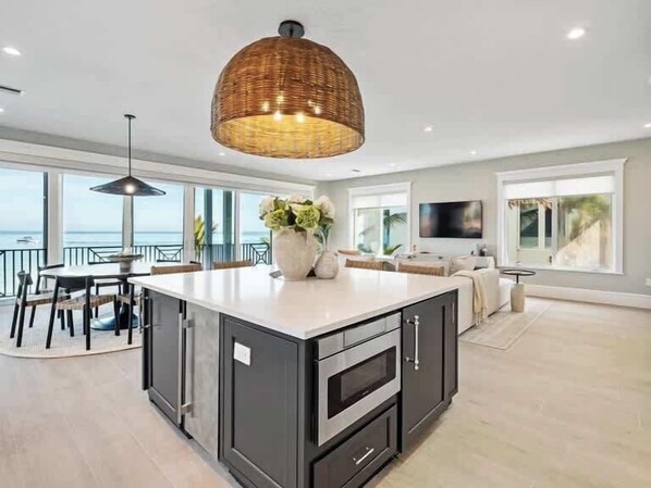 Una cocina moderna con una isla central, armarios oscuros y una lámpara colgante grande.