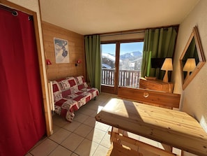 Ein gemütliches Zimmer mit einem hölzernen Bett, einem Holztisch und einem Balkon mit Bergblick.