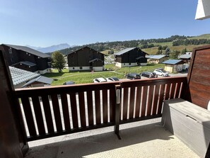 En balkong med utsikt över ett lantligt område, inklusive byggnader och ett bergskedja.