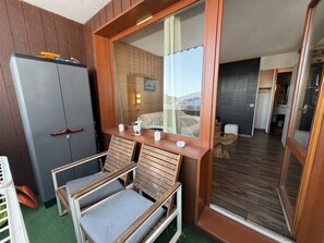 A room with a wooden-framed window, a grey wardrobe, and two wooden chairs with grey cushions. - Cozy apartment, mountain view - 5 guests (Valmorel)