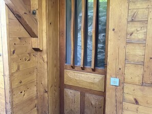 A wooden door with a vertical window, a metal handle, and a small light switch on the wall. - Duplex panoramic mountain view - 8 guests (Les Saisies)
