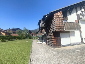 A residential building with a sloped roof, a balcony, and a well-maintained lawn. - Apartment with ski view balcony - 4 guests (Arâches-la-Frasse)