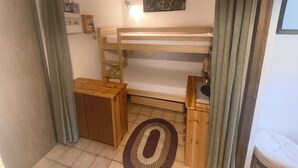 A small, cozy room with a bunk bed, a wooden nightstand, a small table, and a rug on the floor. - Apartment with ski view balcony - 4 guests (Arâches-la-Frasse)