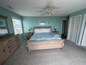 Ein Schlafzimmer mit Bett, Nachttischen, Deckenventilator und einer Tür.