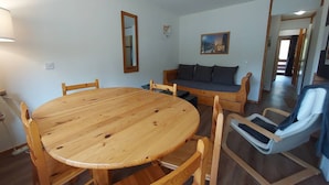 Um quarto com uma mesa redonda de madeira e cadeiras, um sofá e um espelho na parede.