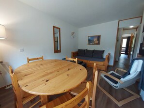 Ein Zimmer mit einem runden Holztisch und Stühlen, einer Couch und einem Spiegel an der Wand.