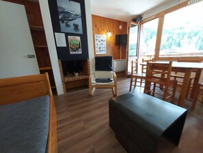 A cozy room with a fireplace, wooden furniture, and a large window offering a view of the outdoors. - Central apartment, view of slopes - 5 guests (Valmorel)
