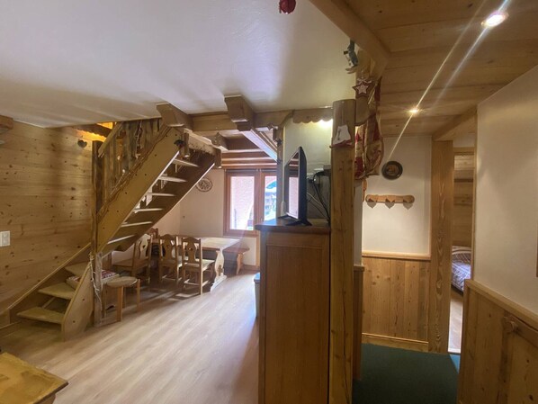 Un interior de madera con una escalera, un televisor y un comedor.