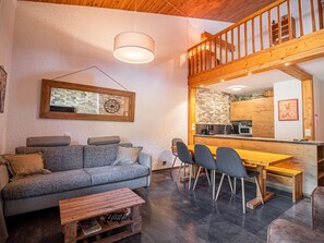 A cozy living area with a sofa, chairs, a coffee table, and a wooden dining table. - Duplex with slope view - Valmorel - 6 guests (Valmorel)