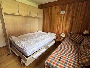 Ein Schlafzimmer mit einem Bett, einem Holzschrank und einem Nachttisch mit Lampe.