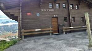 A wooden building with a sign reading 'Premier de Cordée' and a parking sign. - Cozy apartment, parking - 4 guests (Les Saisies)
