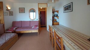 Um quarto acolhedor com sofá, uma mesa de jantar com cadeiras, um espelho e uma estante com objetos.