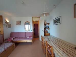 A cozy room with a sofa, a dining table with chairs, a mirror, and a shelf with items. - Apartment with pets allowed - Ski-in access (Valmorel)