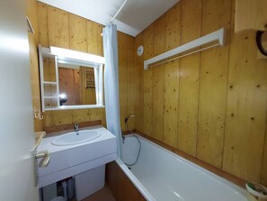 A bathroom with wooden paneling, a white sink, a mirror, and a bathtub. - Apartment with pets allowed - Ski-in access (Valmorel)
